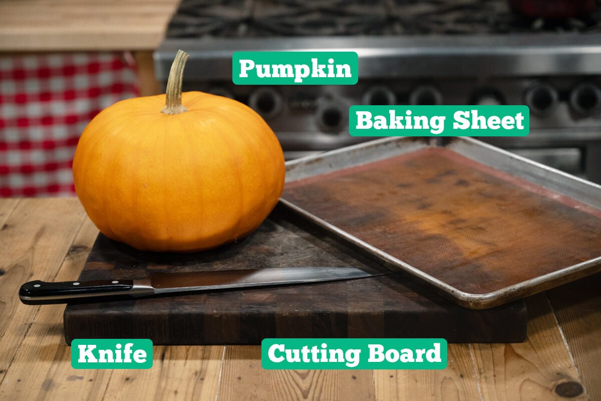 Pumpkin puree supplies and ingredients: pumpkin, baking sheet, knife, and cutting board.