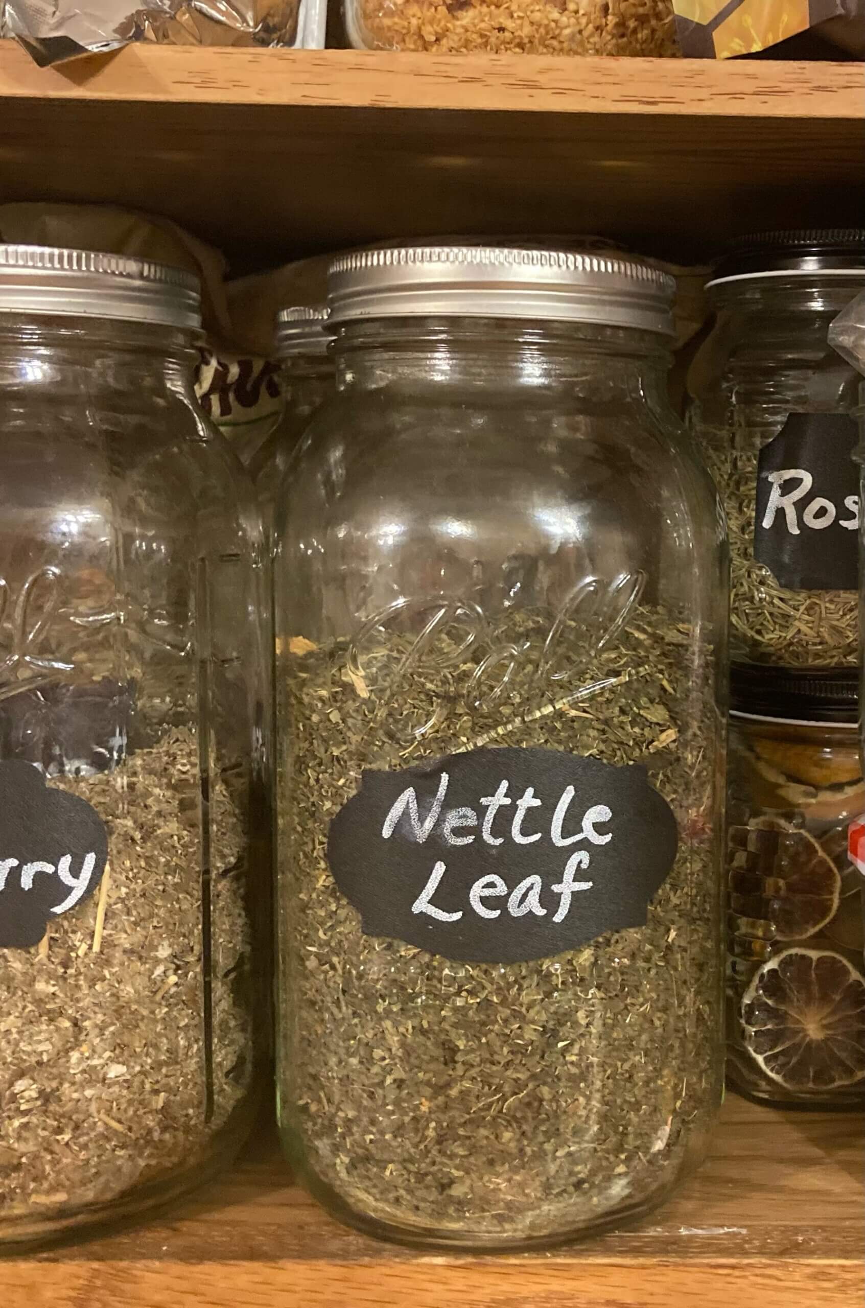 Jars of herbs on cupboard shelf.