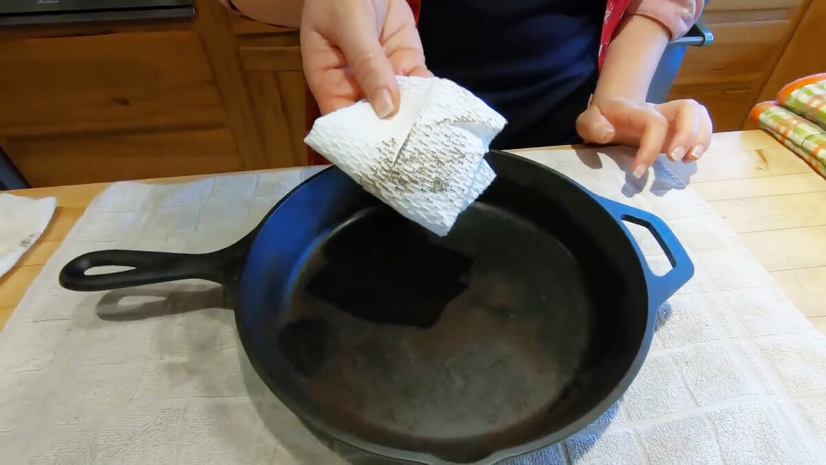 A paper towel showing residual oil residue after wiping a cast iron pan.