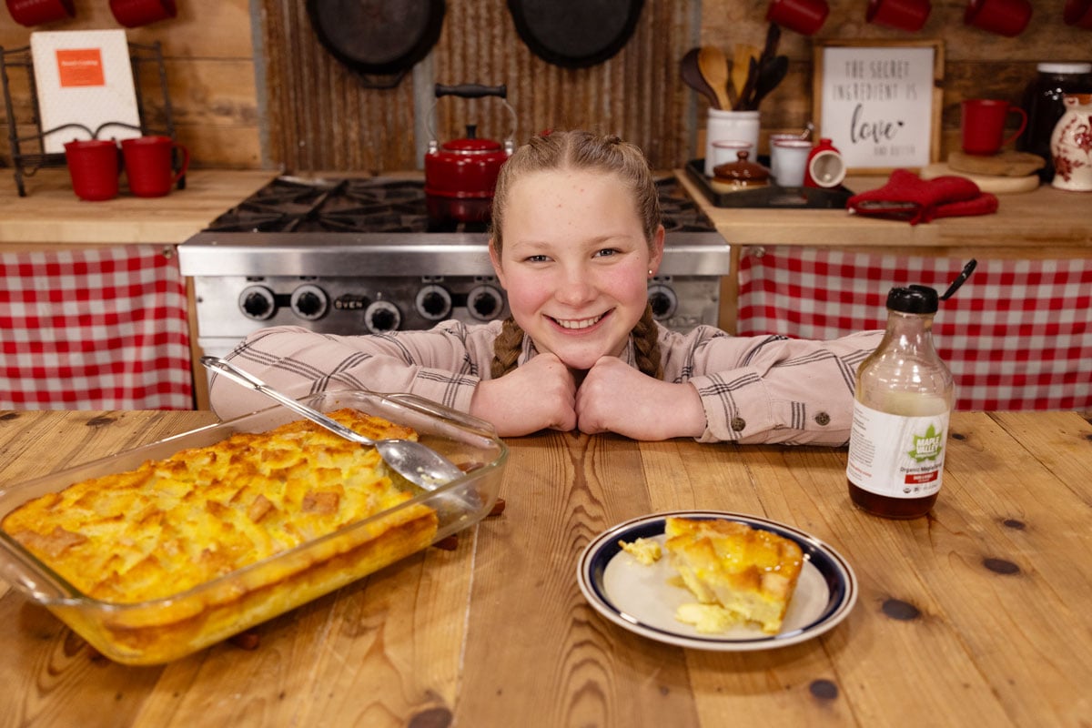 A girl standing in the kitchen with a French toast souffle recipe.