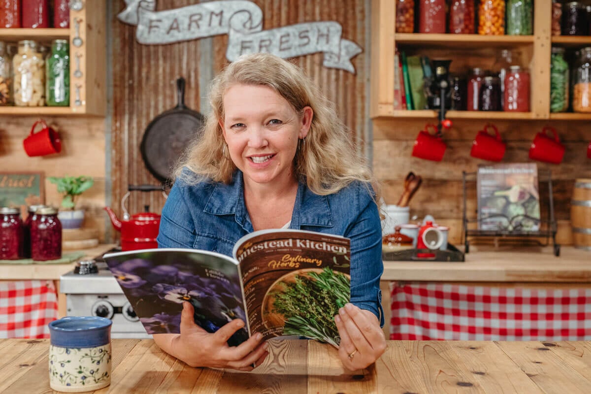 Carolyn from Homesteading Family flipping through a copy of the Homestead Kitchen magazine