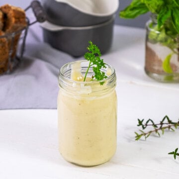 A Mason jar filled with cream of chicken soup and garnished with fresh herbs.