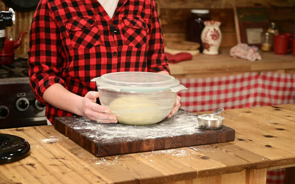 Sourdough dinner roll dough rising in a bowl.