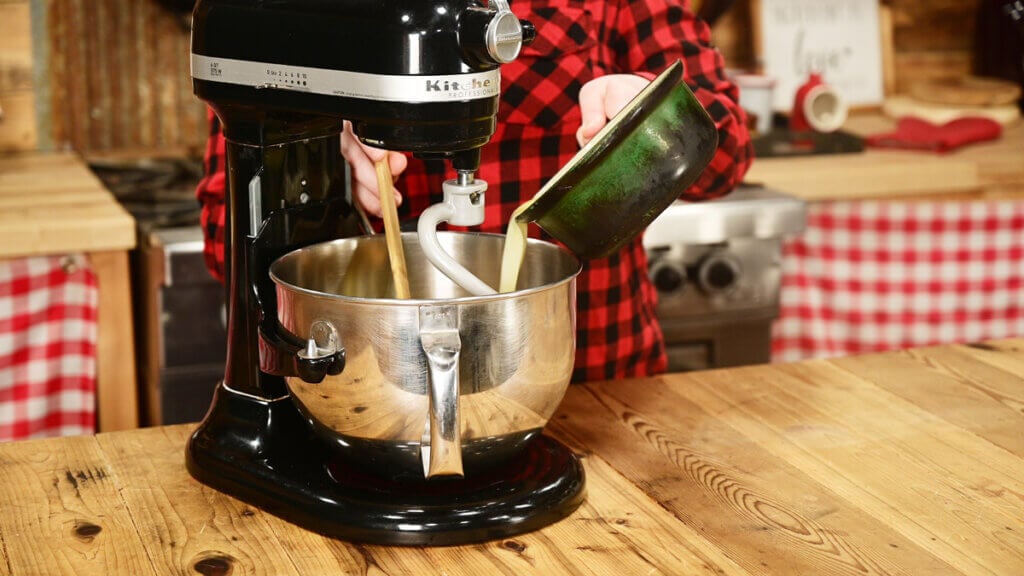 Buttermilk being poured into a stand mixer.
