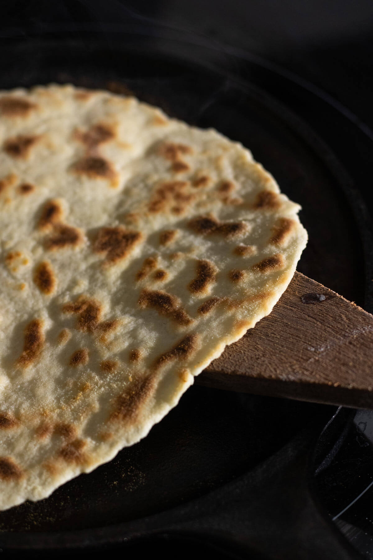 Sourdough discard tortilla cooking in a cast iron skillet.