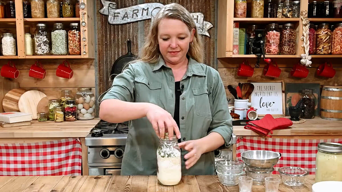 A woman placing a lid on a jar of dry soup mix.