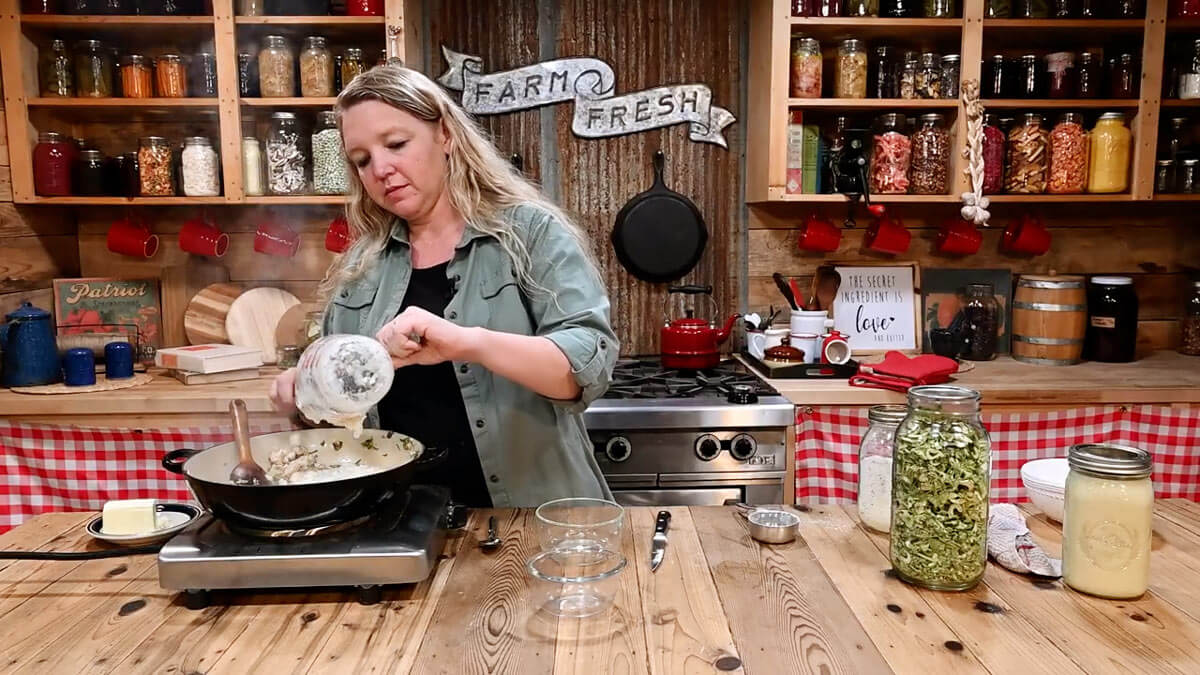 A woman adding chicken broth mixed with dry soup mix to a skillet.