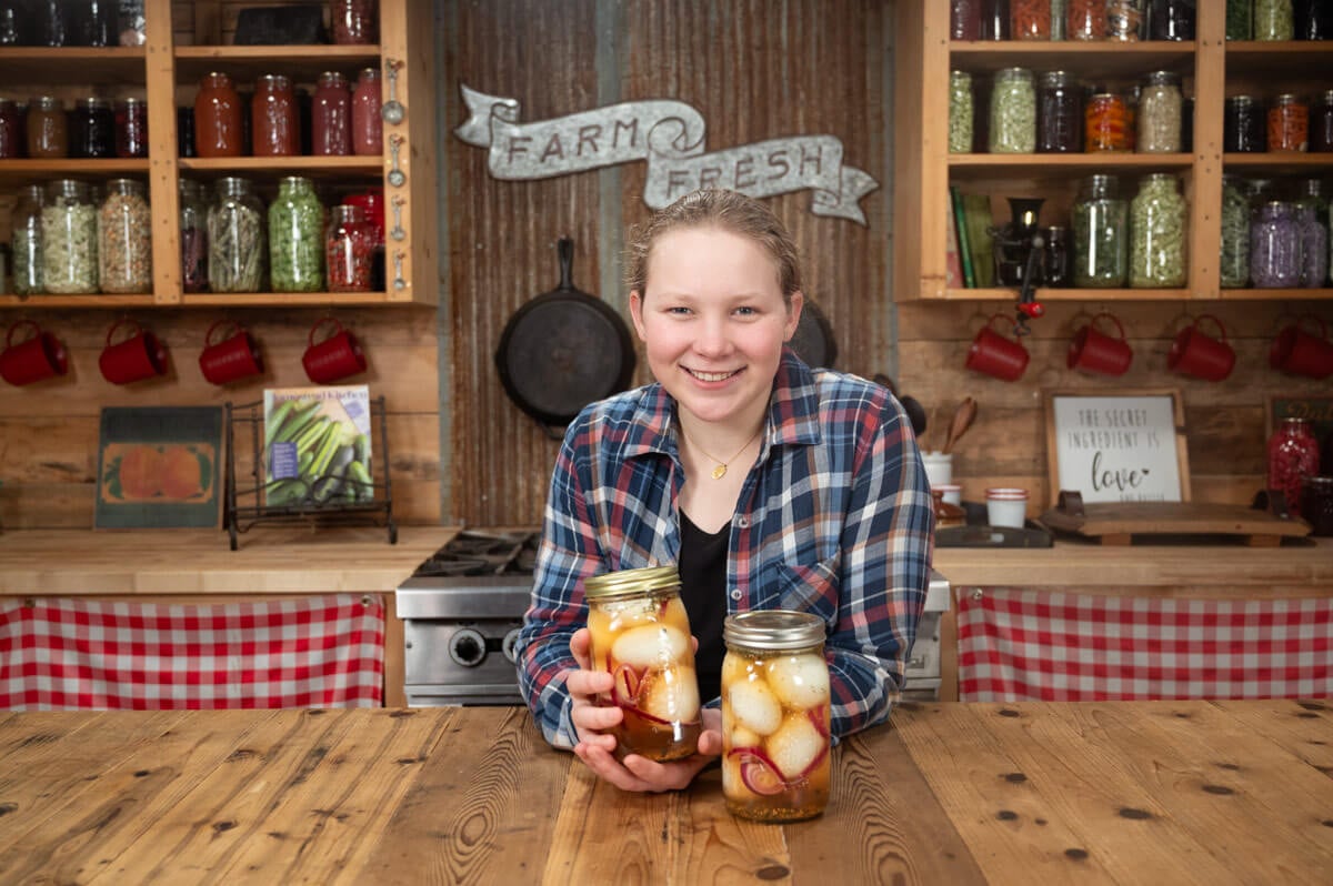 A girl holding up a jar of pickled eggs.