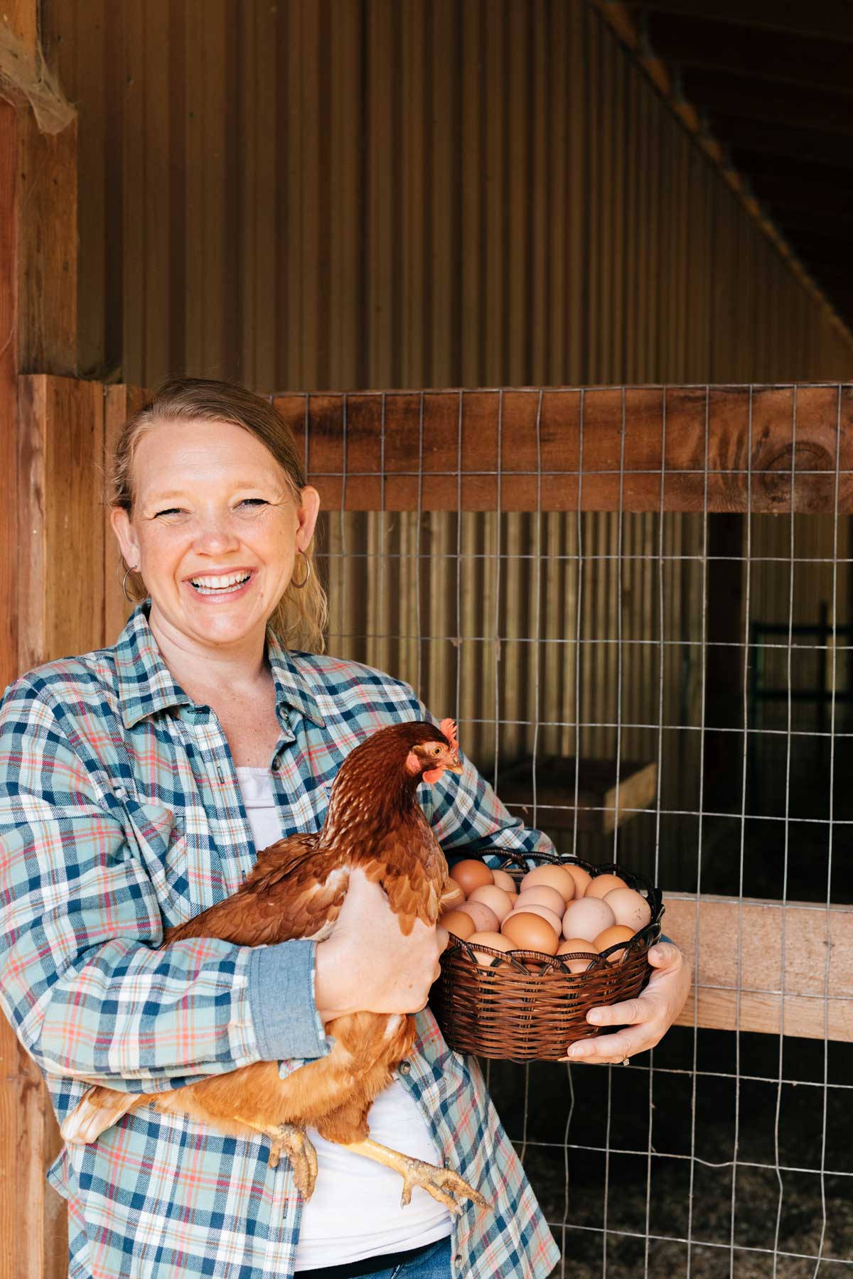 A woman holding a basket of eggs in one arm and a chicken in the other.
