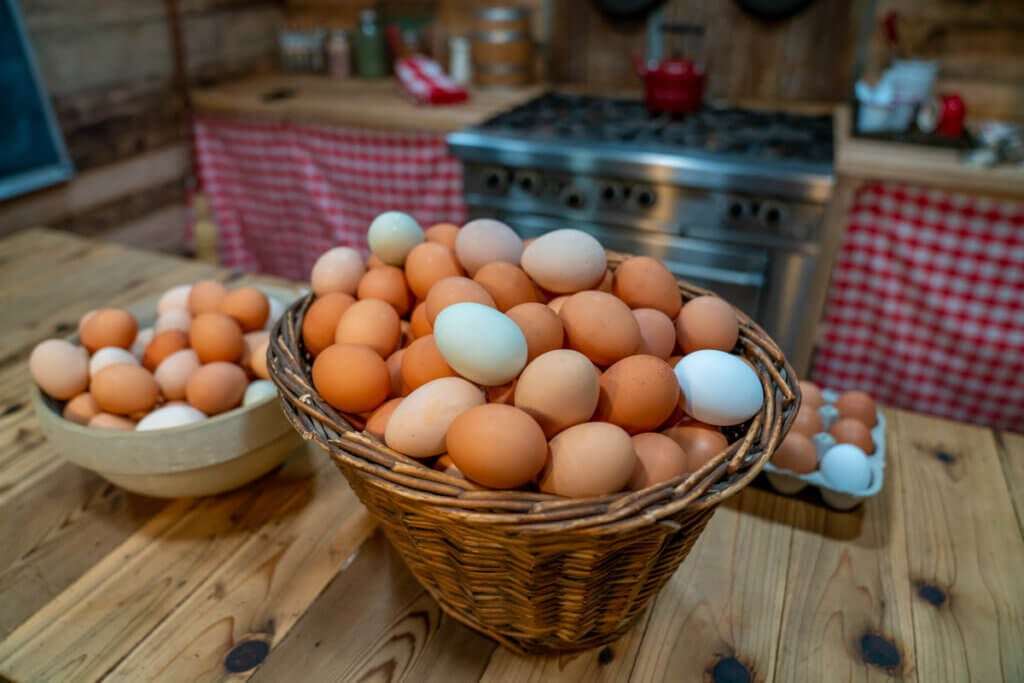 White and brown eggs in a basket on the kitchen counter.