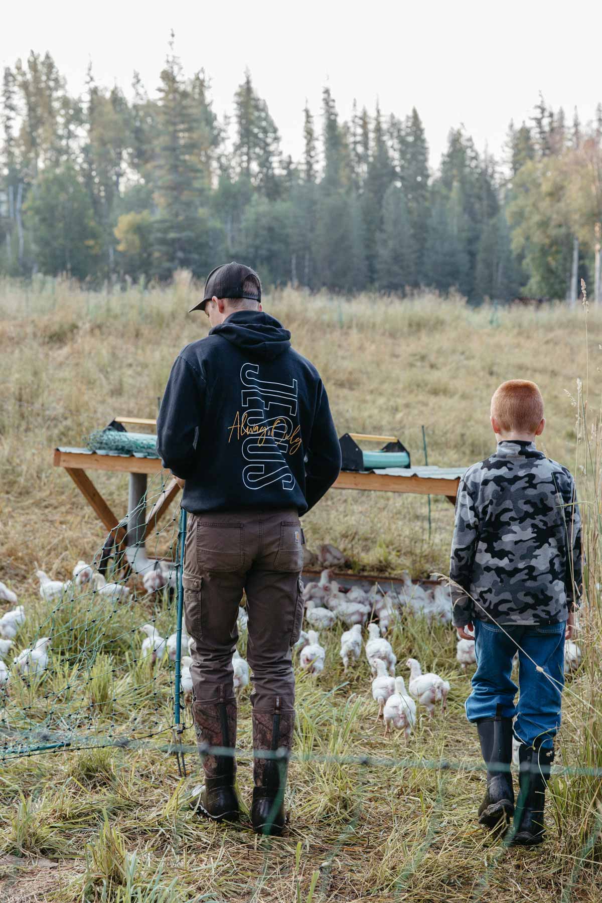 An older and younger brother with a flock of meat chickens.