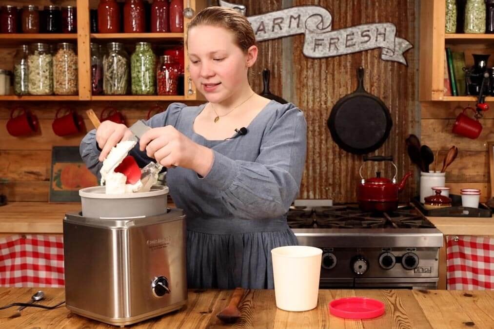A young girl making homemade ice cream in an ice cream maker.