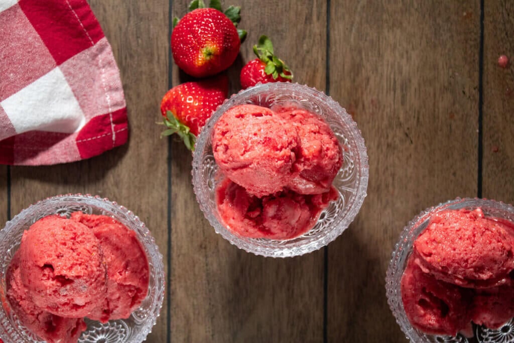 A bird's eye view of three serving dishes filled with strawberry sorbet.