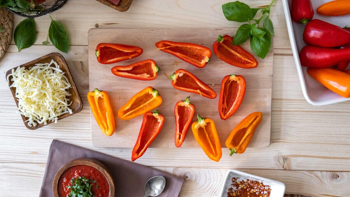 Halved bell peppers sitting face up on a cutting board.