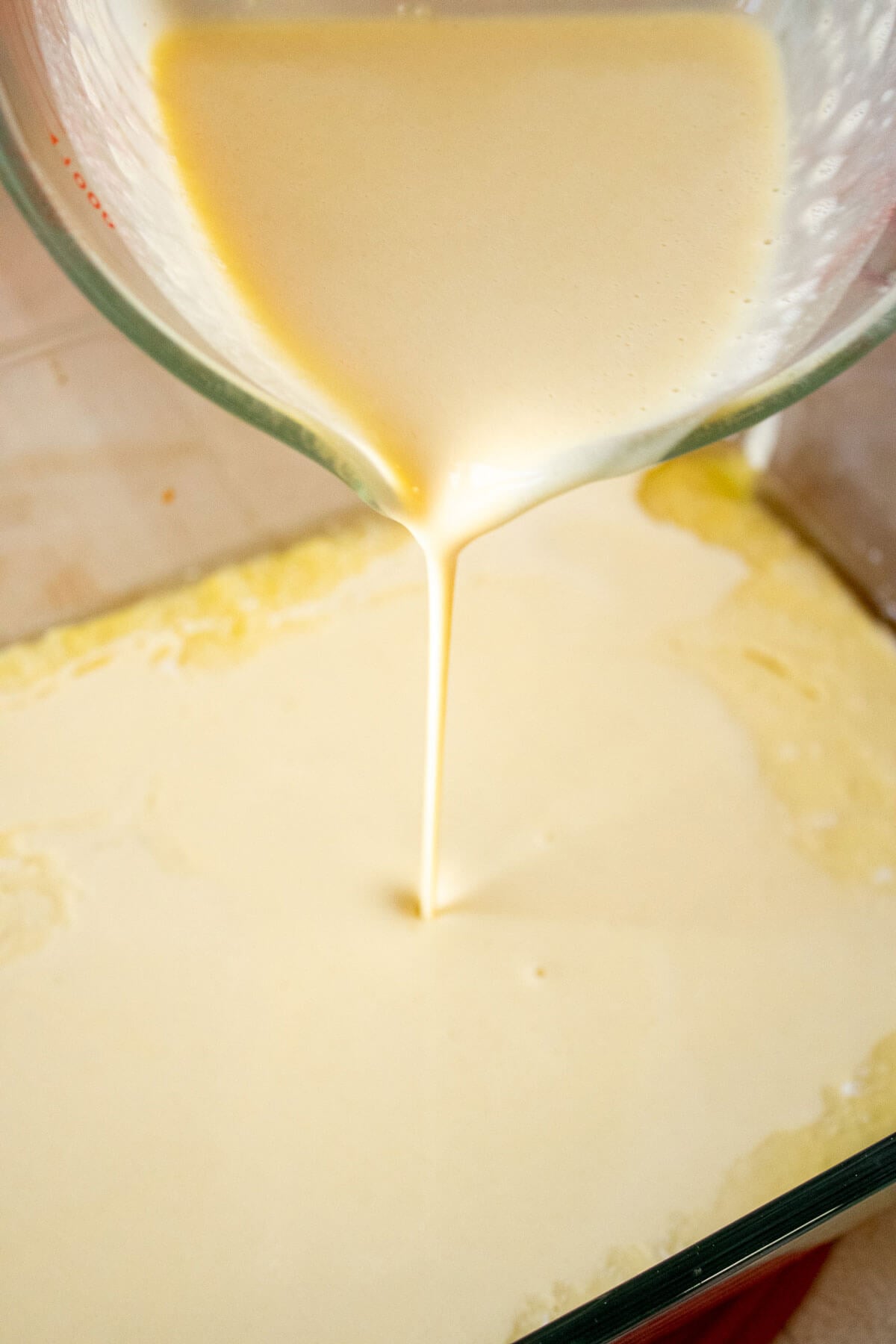 Pouring German pancake batter from a blender into a baking dish.