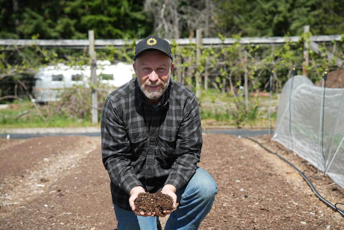 A man holding a handful of compost in the garden.