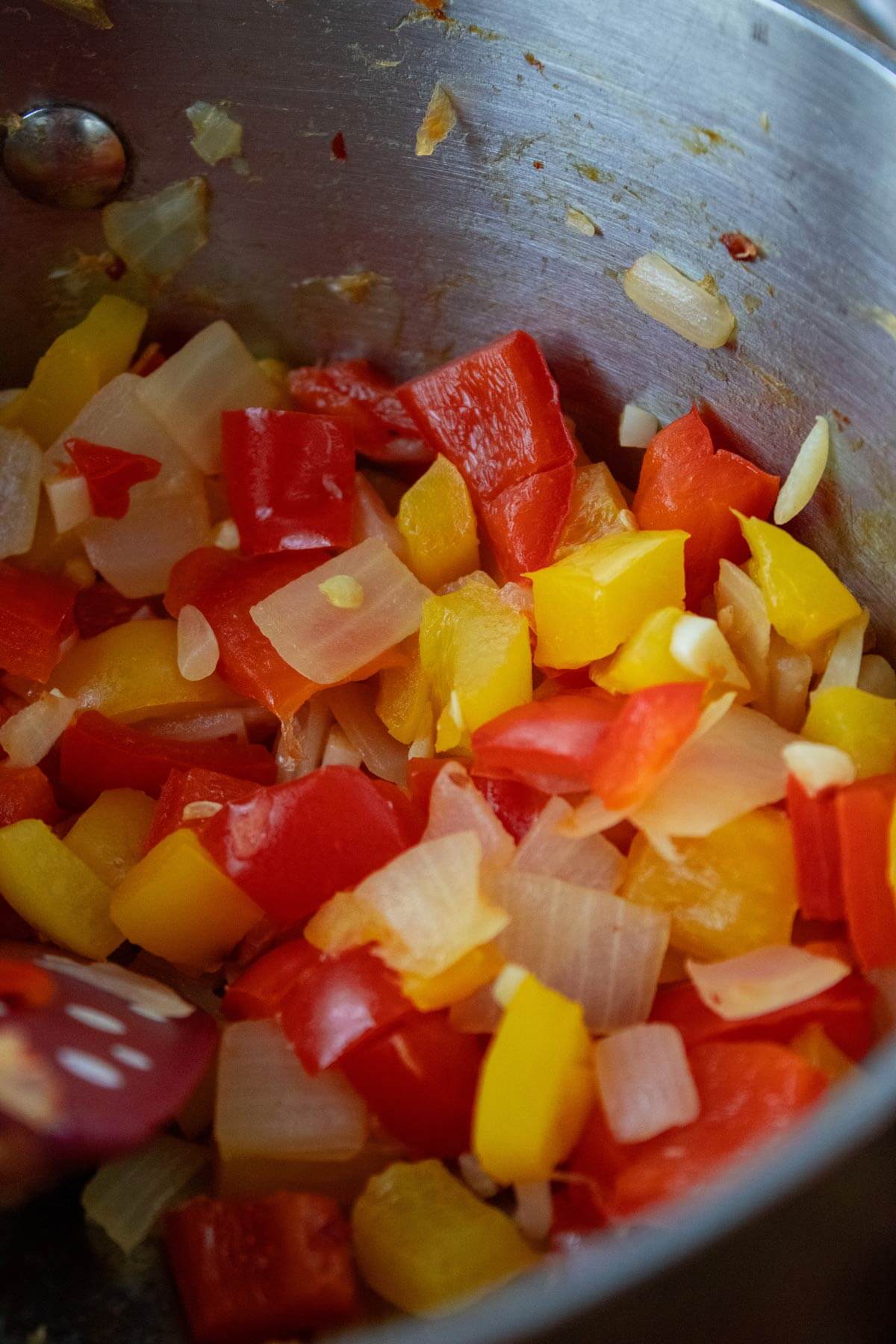 Peppers and onions sauteing in a pan.