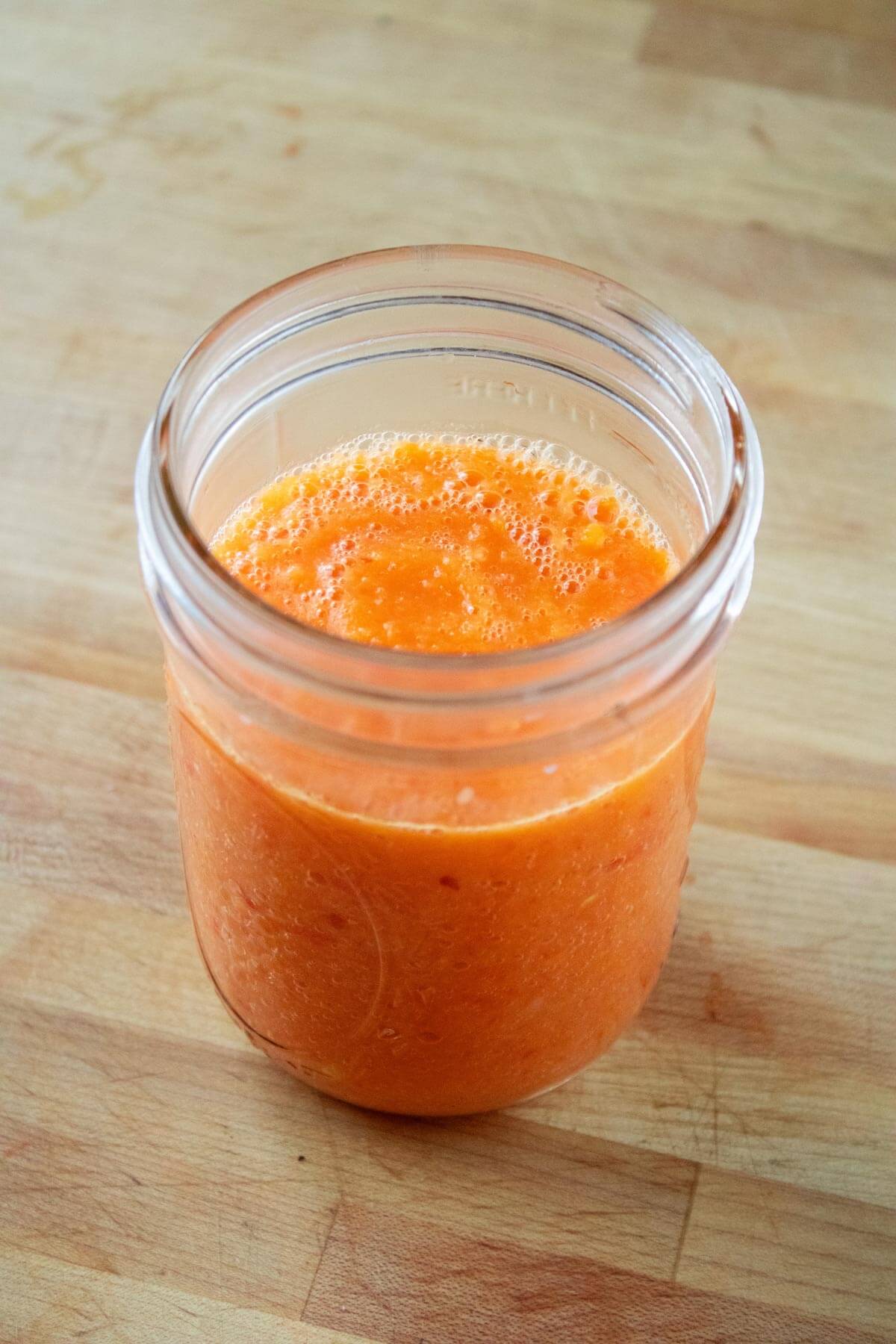 Blended fermented pepper sauce transferred to a glass jar, and ready to ferment.