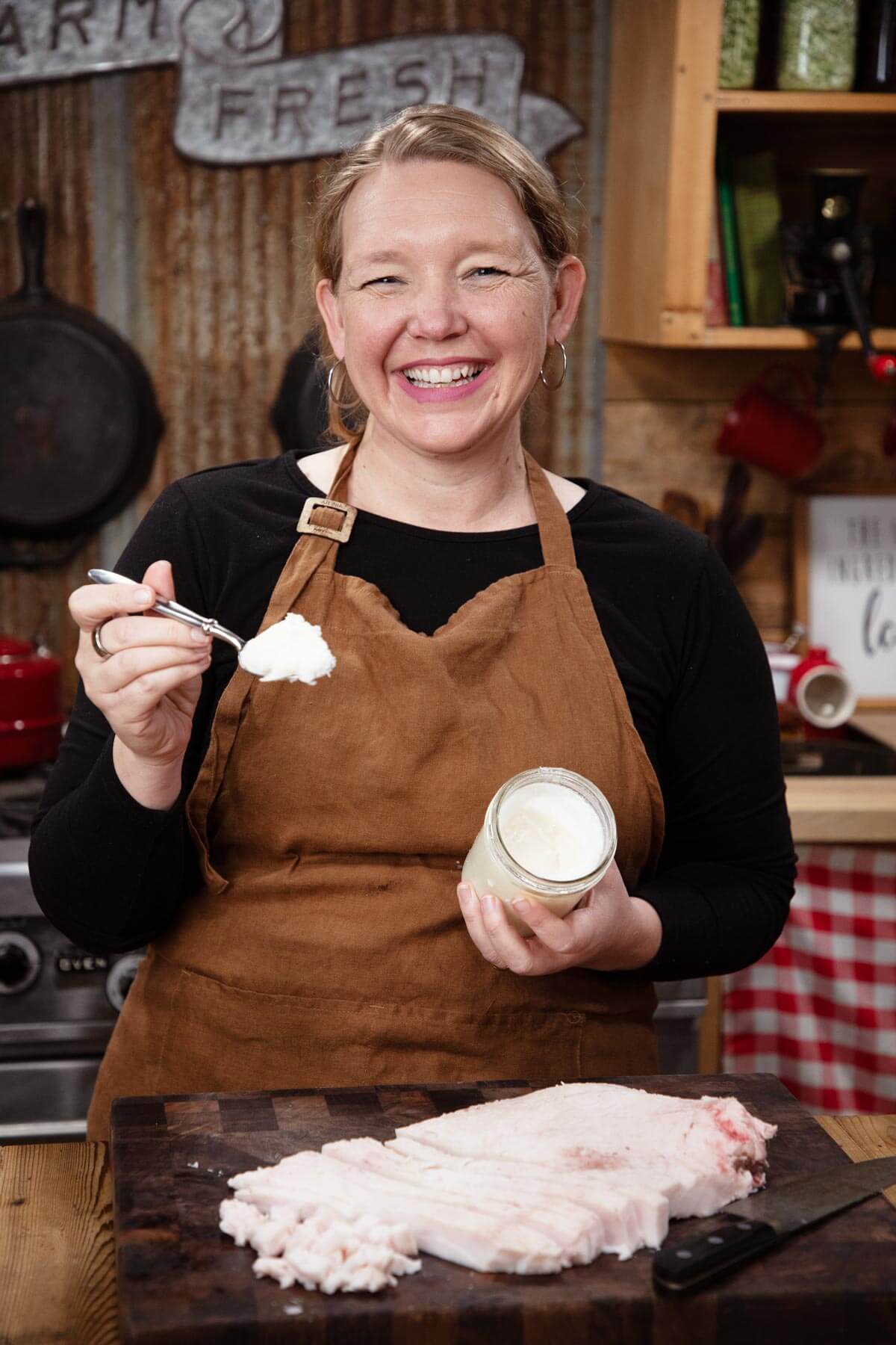 A woman scooping a spoonful of lard out of a jar.