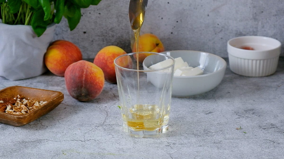 A spoon drizzling olive oil into a jar.