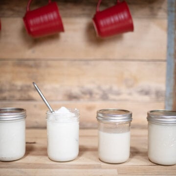 Four jars of rendered lard sitting on a counter.
