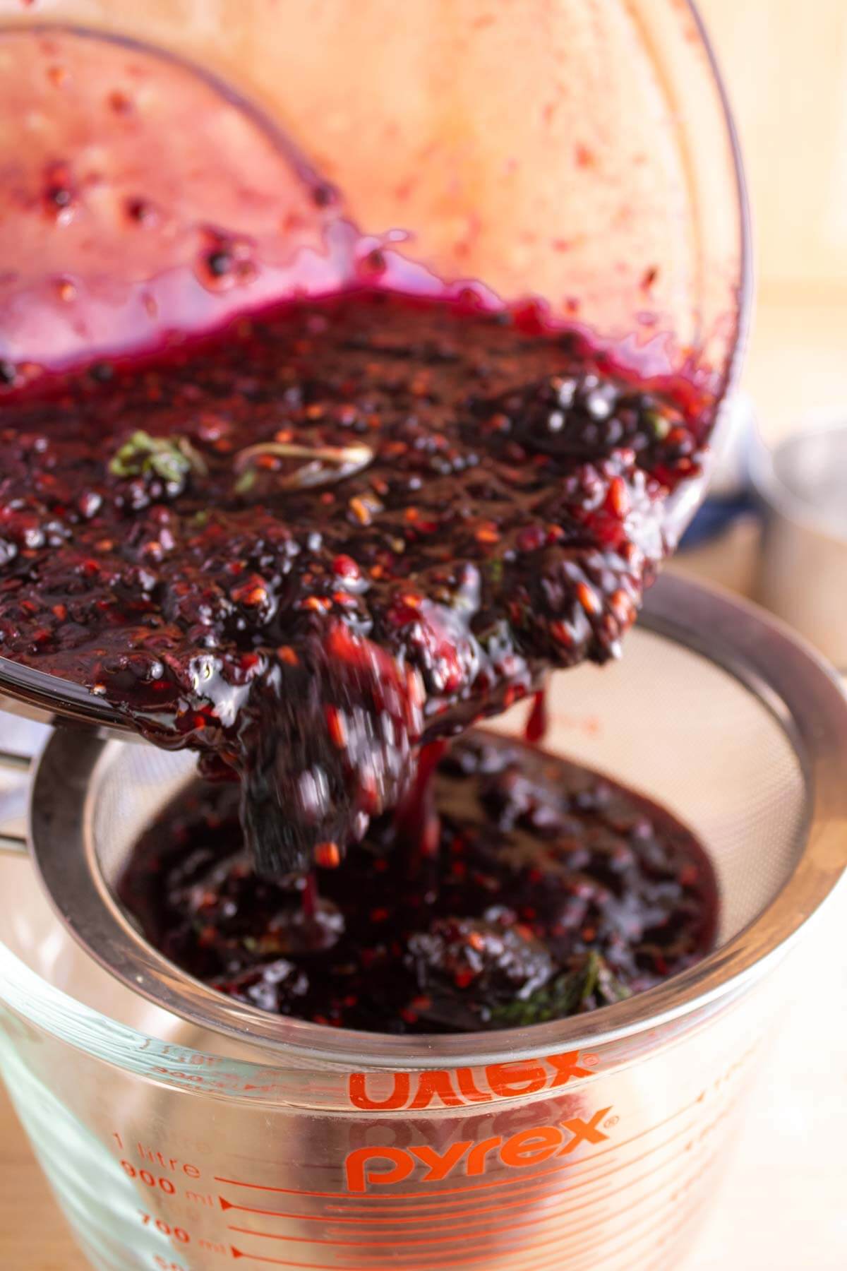 Macerated blackberries being strained.
