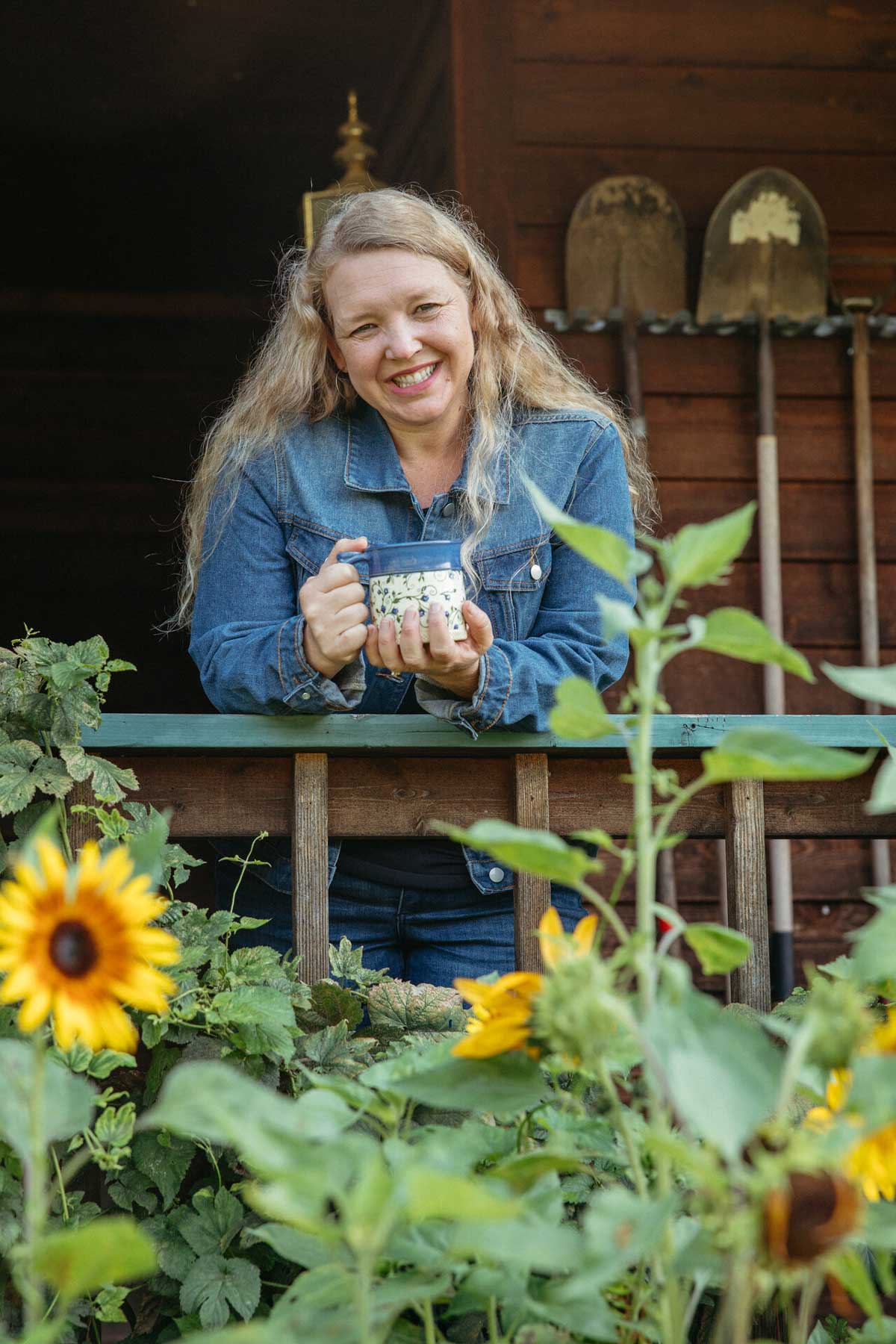 A woman on her deck holding a cup of coffee.