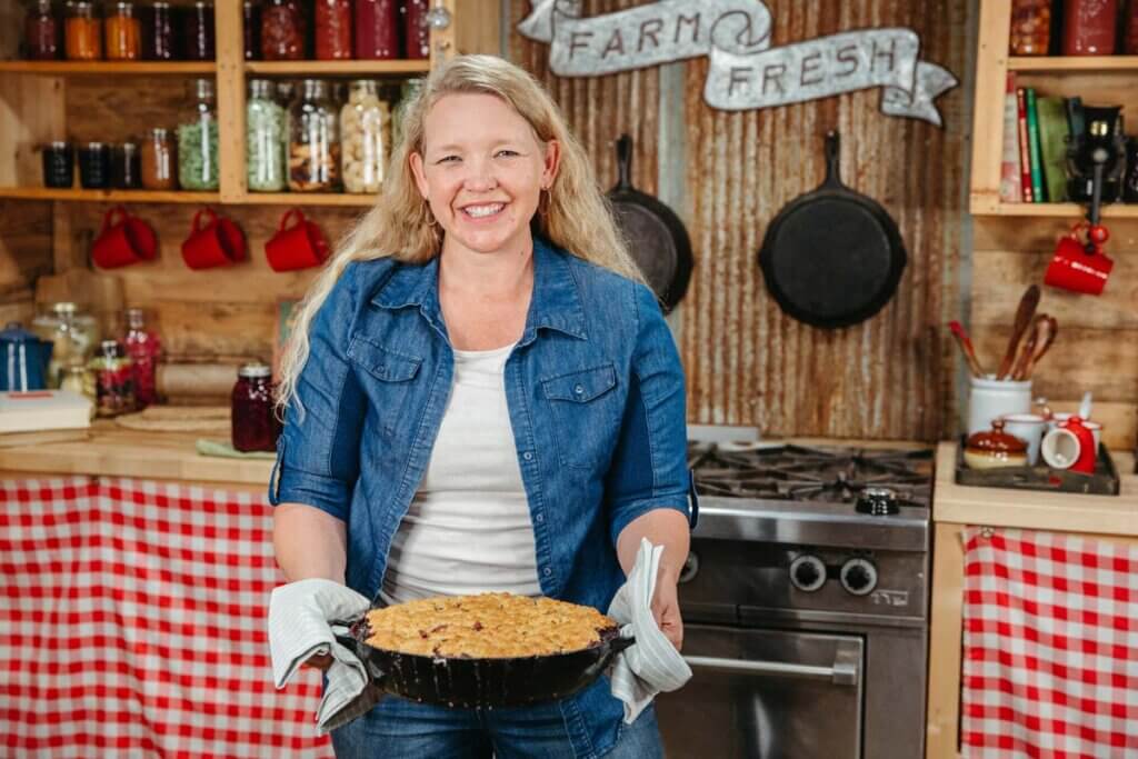 A woman holding a fresh baked berry cobbler.