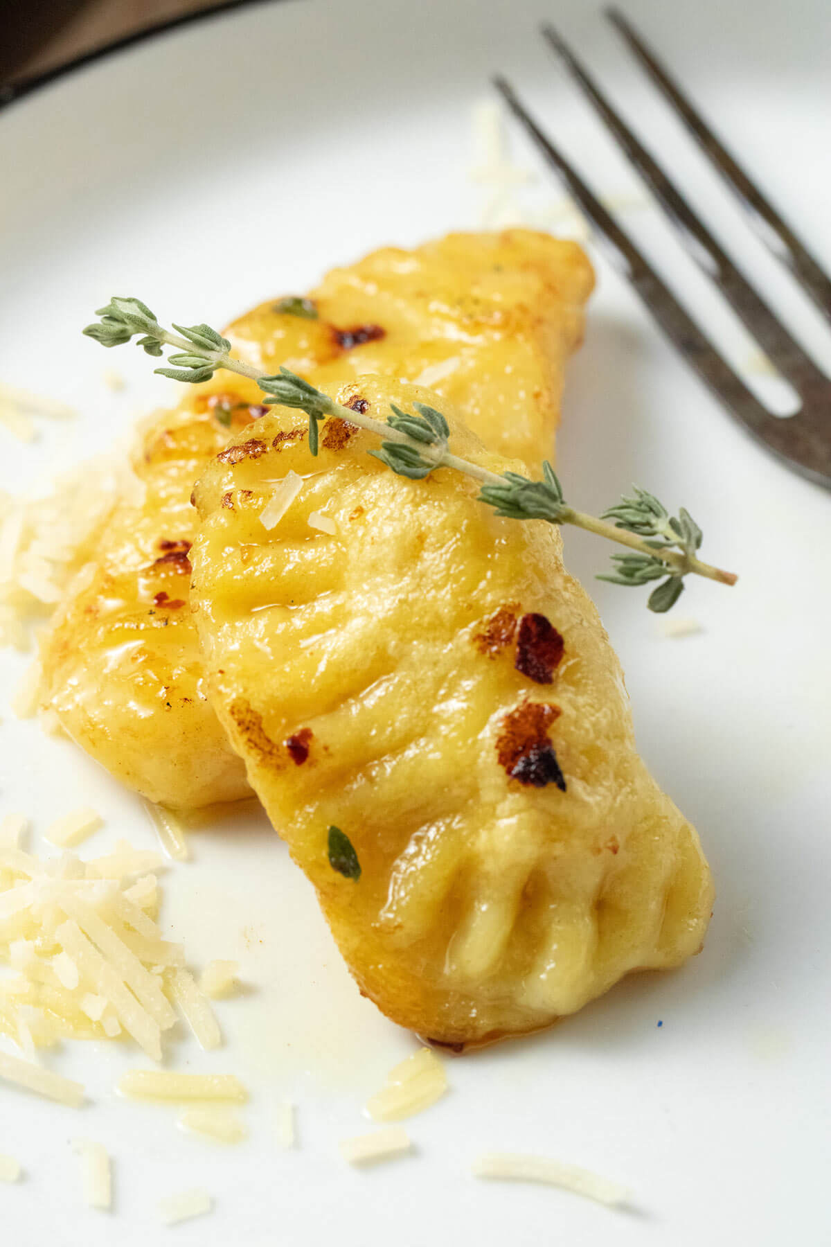 Gnocchi served on a white plate and garnished with fresh thyme.