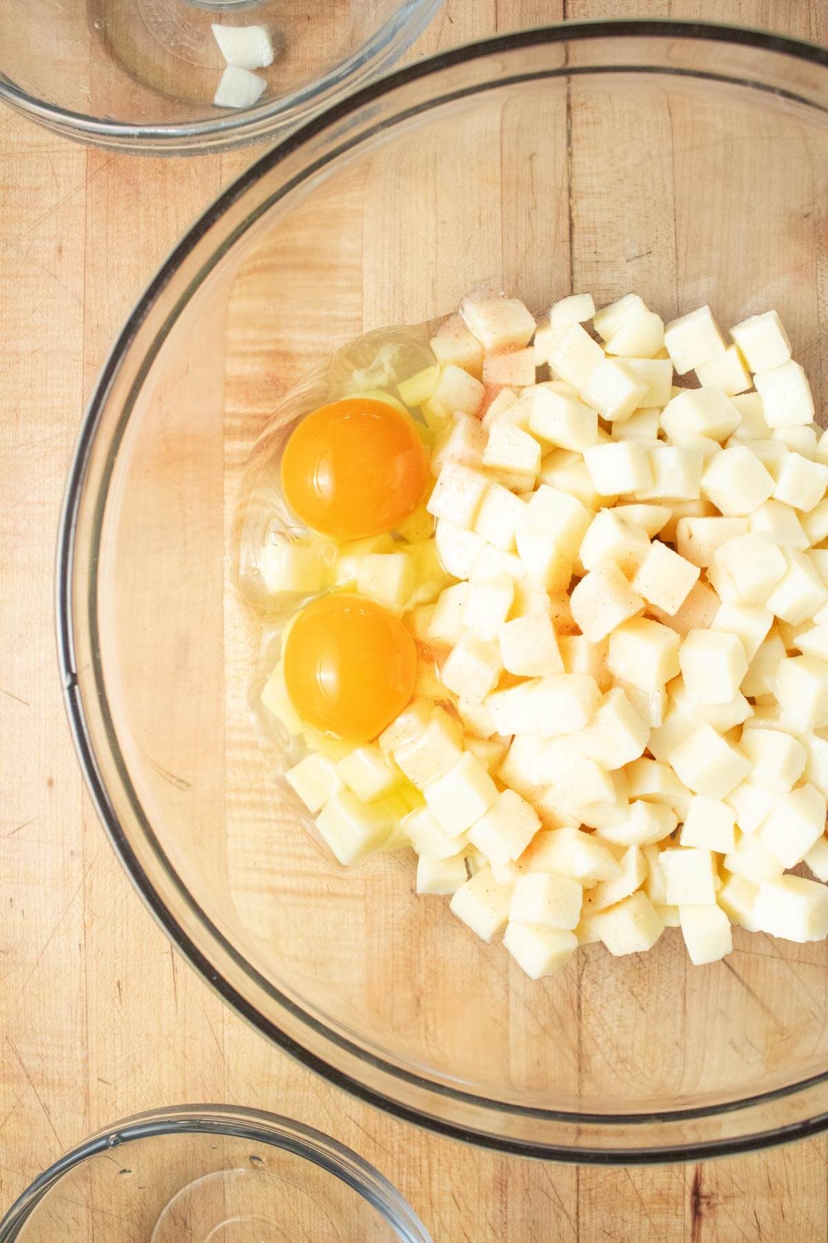 A mixing bowl with raw eggs and cooked potatoes.