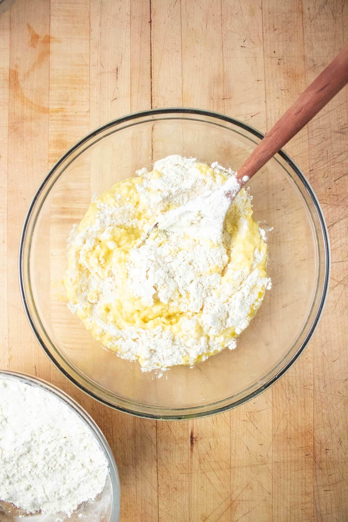 A fork mixing homemade gnocchi ingredients in a glass bowl.