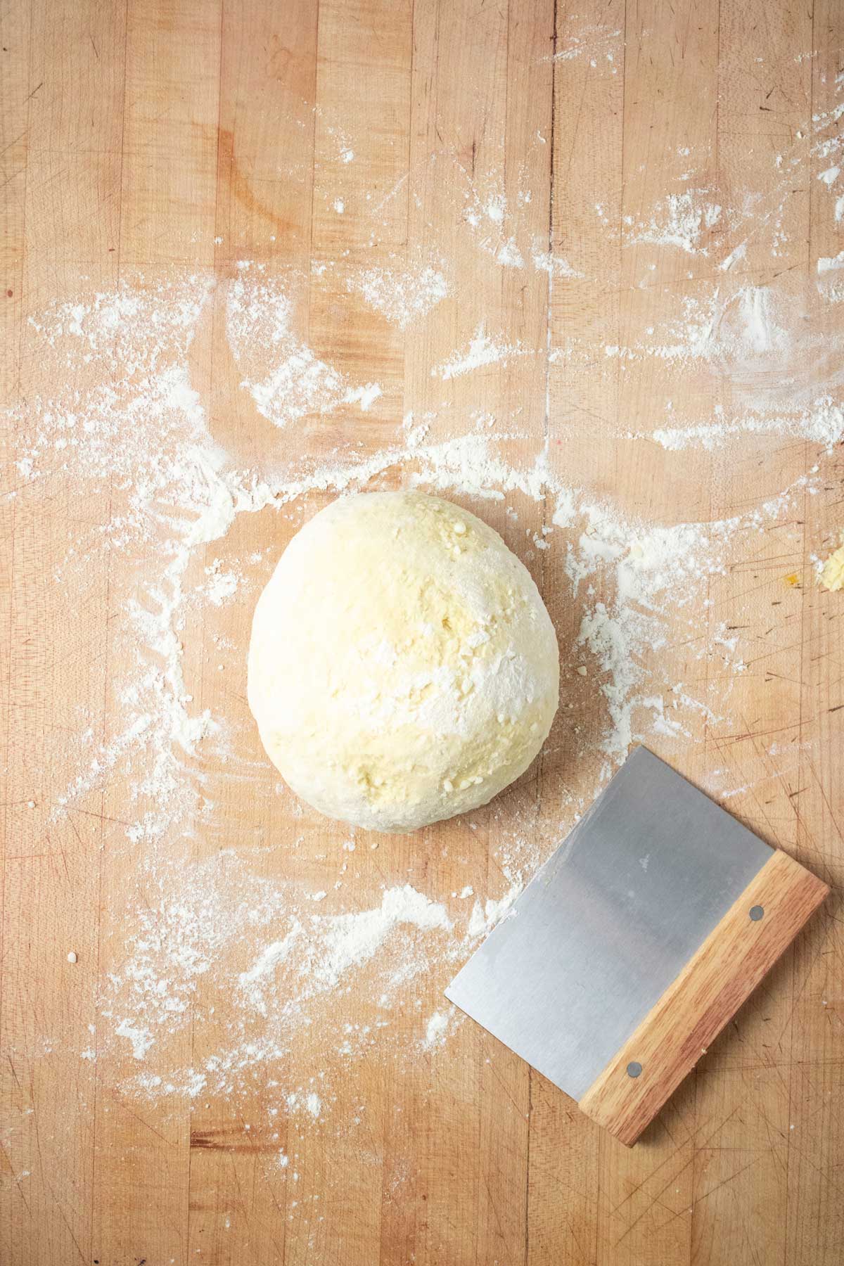 A ball of gnocchi dough on a floured surface.