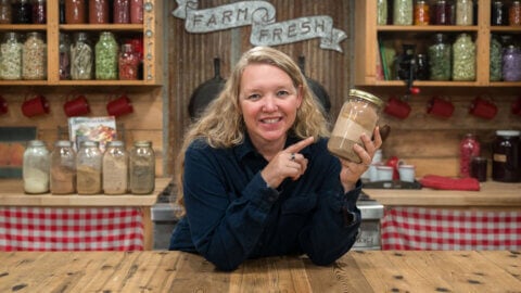 A woman holding a jar of powdered herbs.