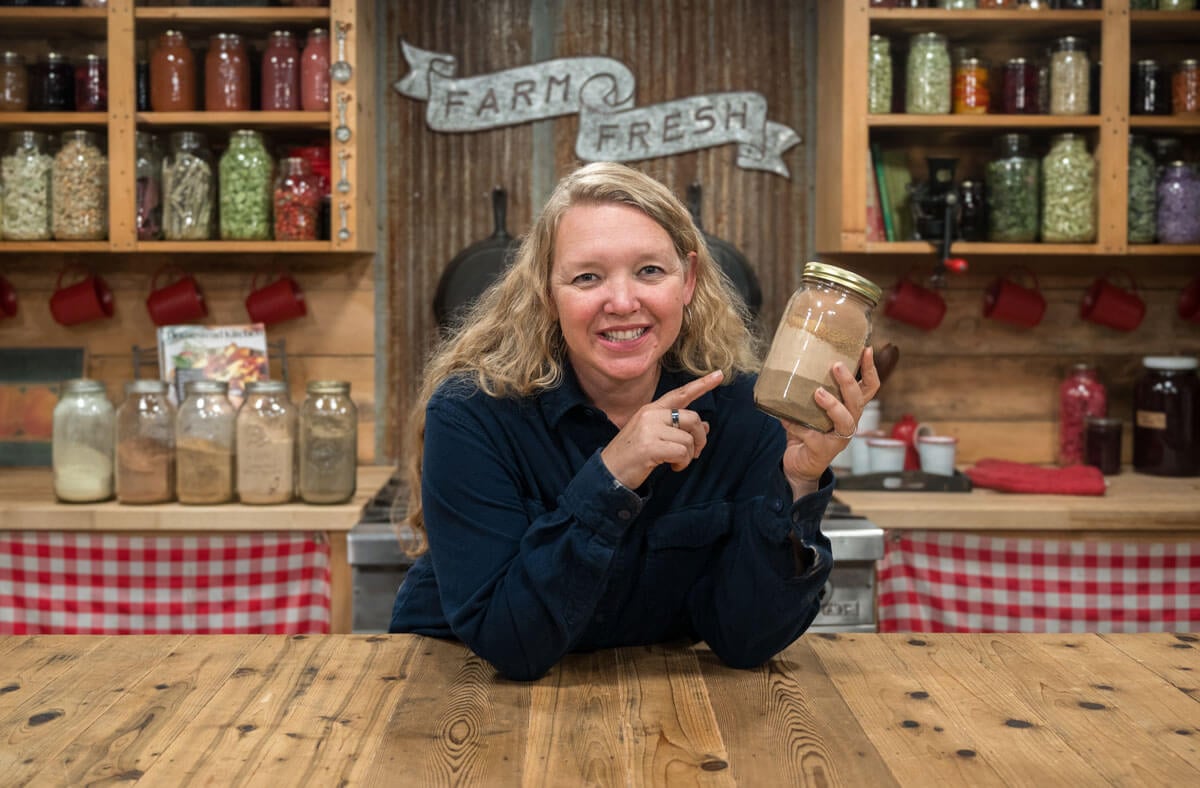 A woman holding a jar of powdered herbs.