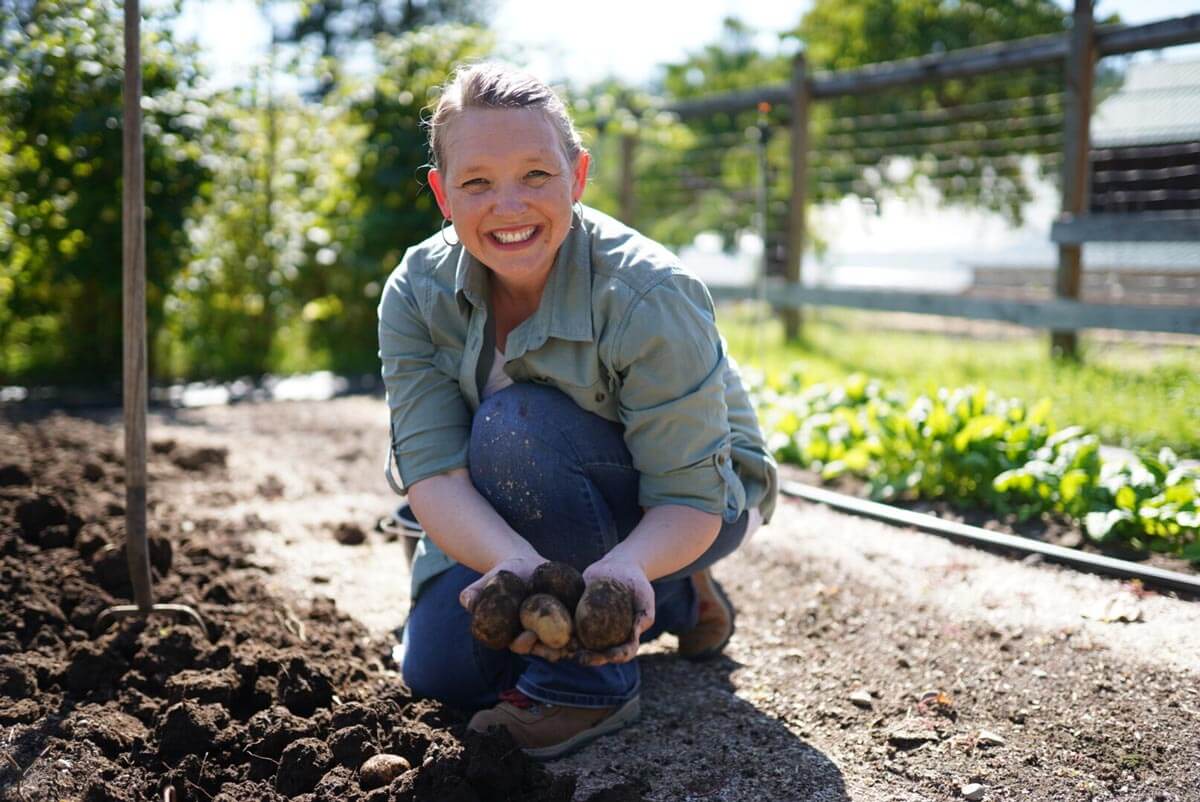 A woman holding potatoes she just dug up from the garden.