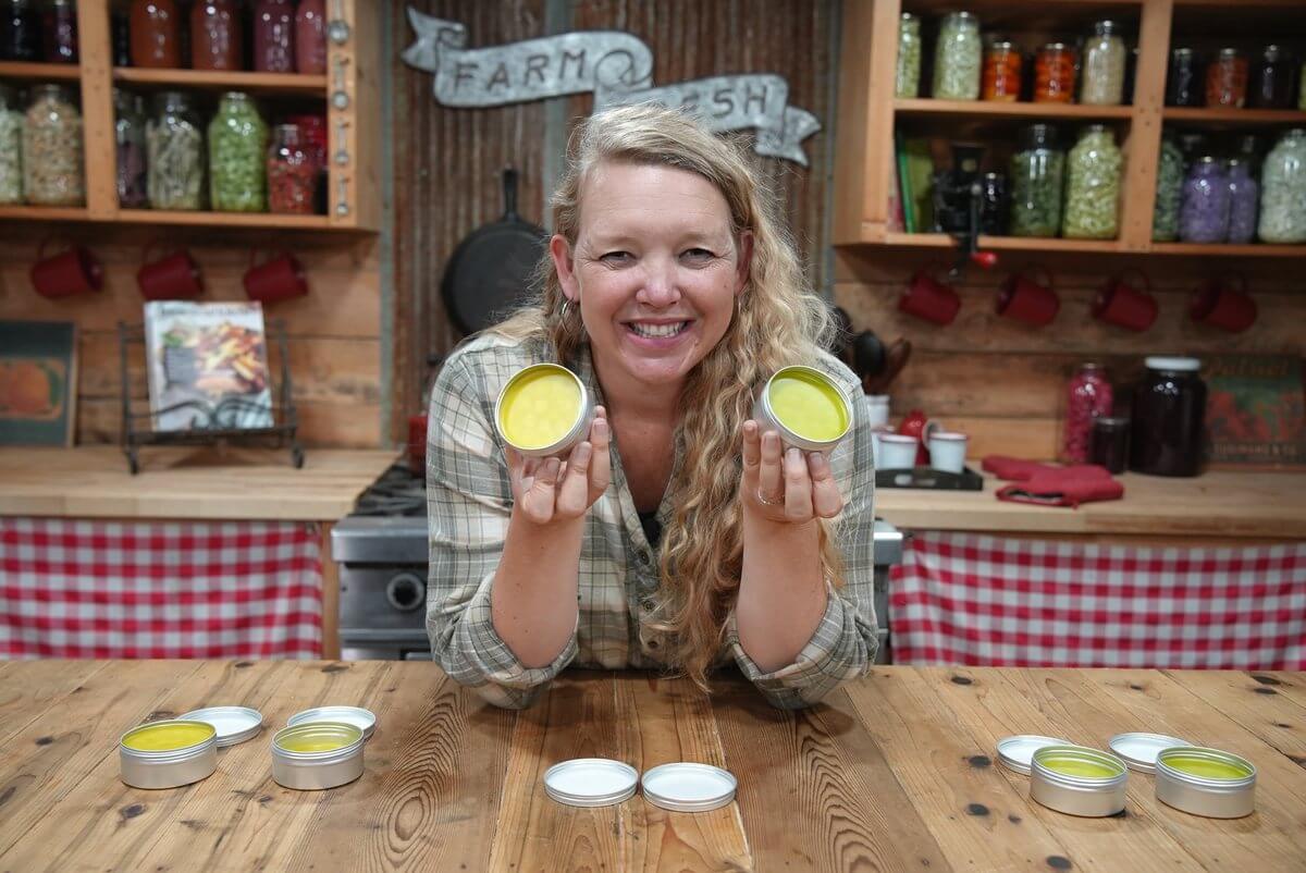 A woman holding up two jars of homemade burn salve.