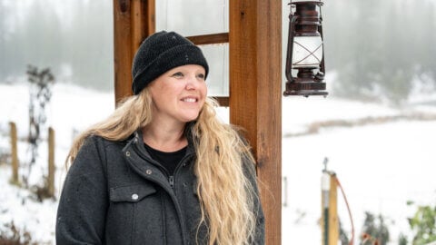 A woman standing beside an arbor with a snowy background.