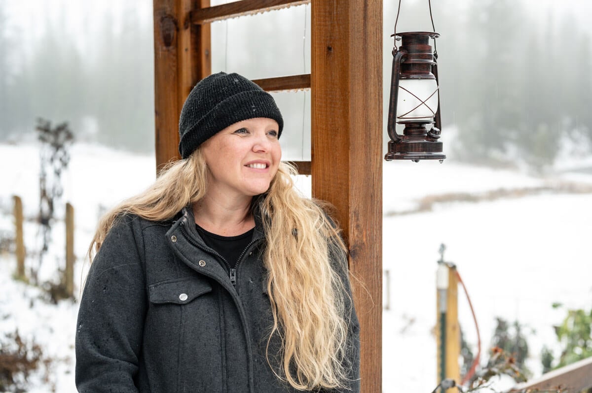 A woman standing beside an arbor with a snowy background.
