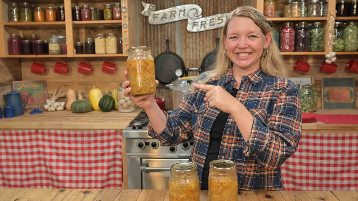 A woman holding up a jar of home-canned chicken and gravy.