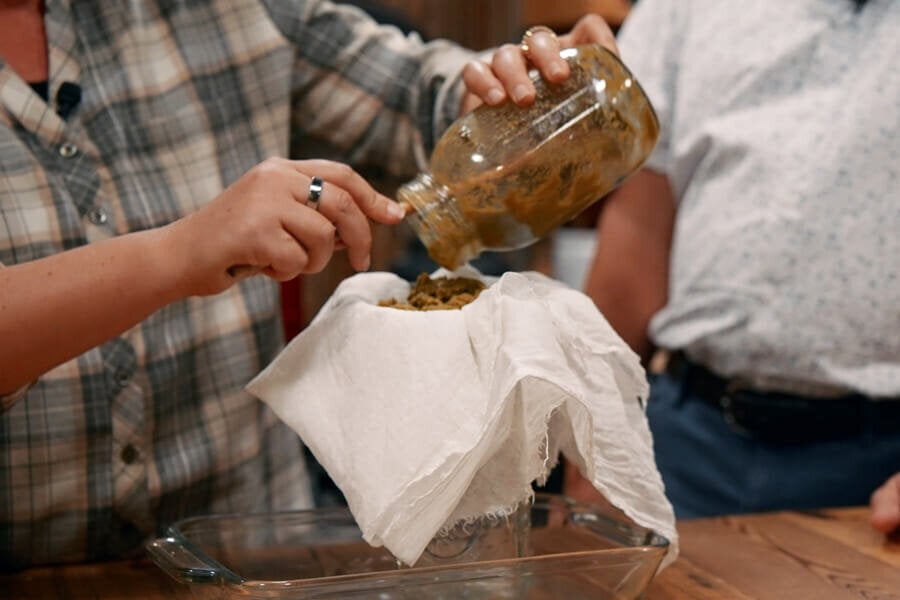 A hops tincture being strained into a jar.