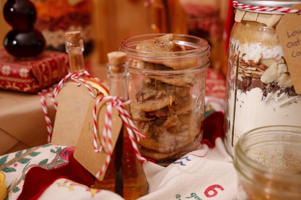 Jar of fruitcake cookies with a gift tag beside holiday decorations.