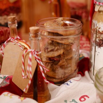 Jar of fruitcake cookies with a gift tag beside holiday decorations.