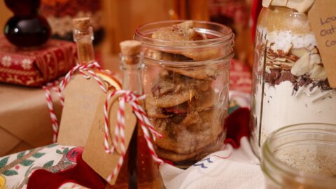 Jar of fruitcake cookies with a gift tag beside holiday decorations.