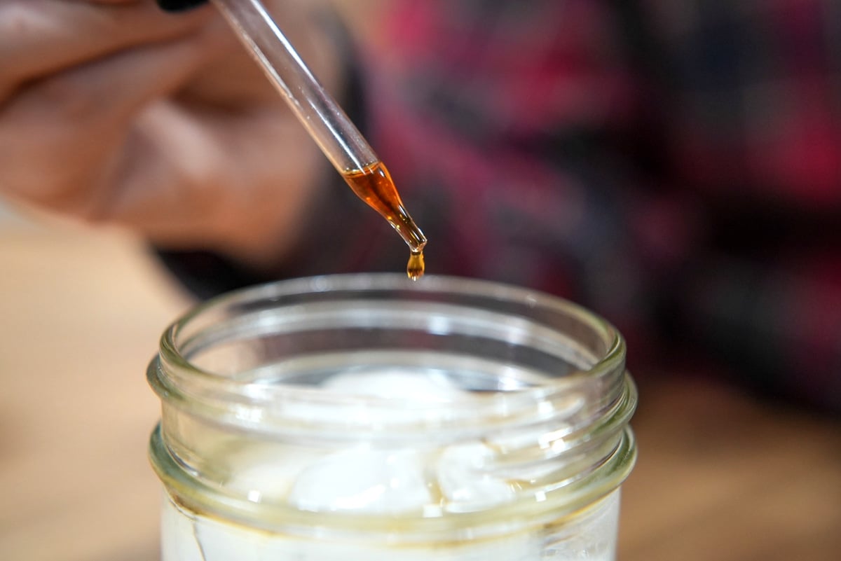 Herbal bitters being added to a glass of sparkling water.