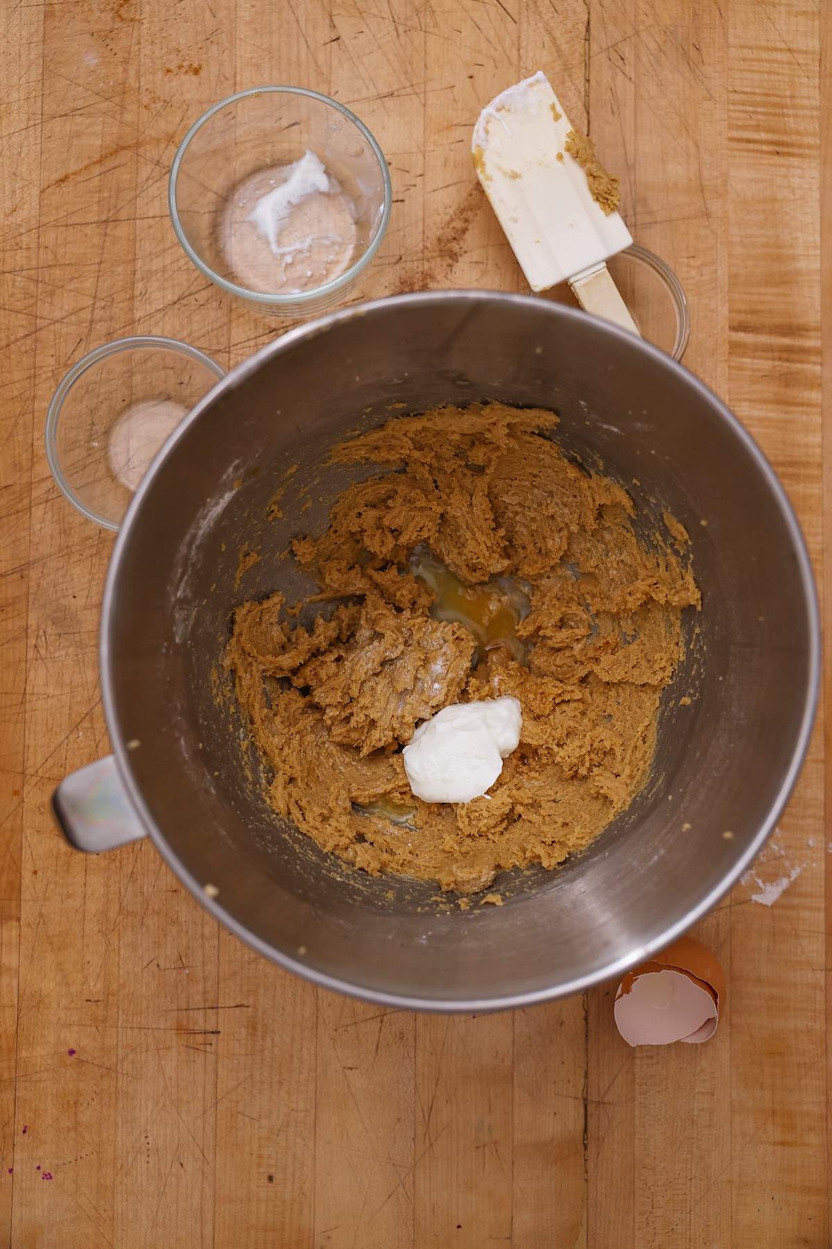 Cookie dough in a stand mixer bowl with a spatula resting nearby.