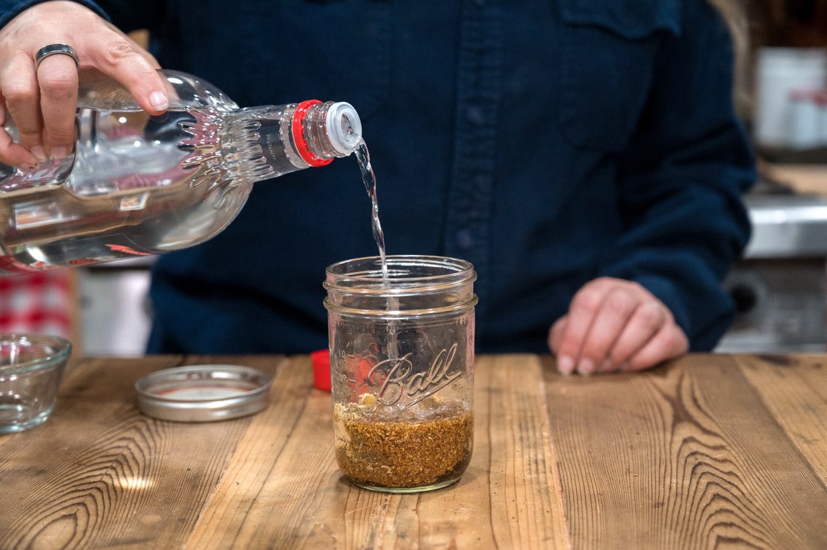 Alcohol being poured over dried herbs.