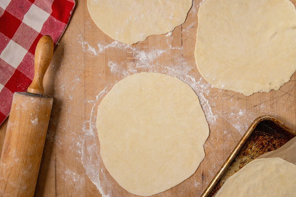 Rounds of pie dough on a floured counter beside a rolling pin.
