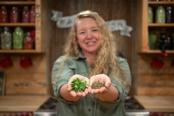 Carolyn_Dried-Herb_Fresh-Herb A woman holding dried herbs in one hand and fresh herbs in the other.