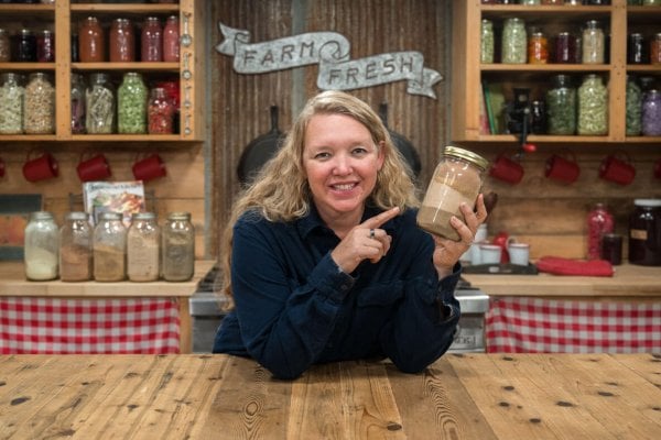 A woman holding a jar of powdered herbs.