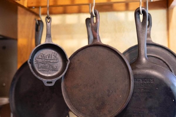 Cast iron pans hanging from a ceiling rack.